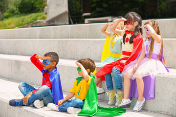 Canvas Print - Cute little children dressed as superheroes sitting on stairs outdoors