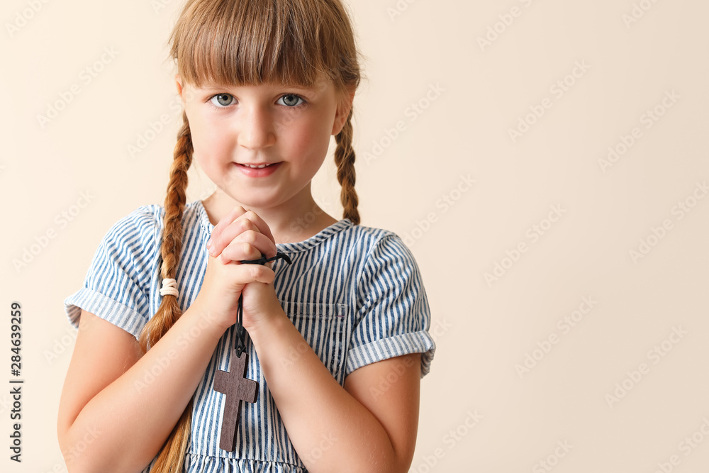Little girl praying on light background