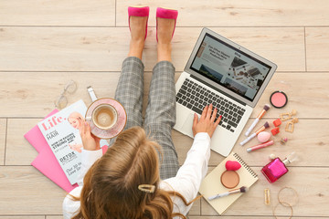 Wall Mural - Female beauty blogger with laptop and cup of coffee sitting on wooden floor, top view