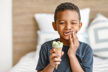 Little African-American boy with sensitive teeth and cold ice-cream at home