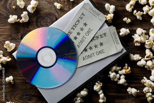 Fotografía Movie tickets, DVD or blu ray disc and popcorn on dark wooden table background