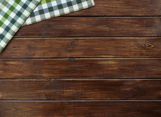 Two checkered cloth napkin on a brown wooden table from boards. Top view with copy space.