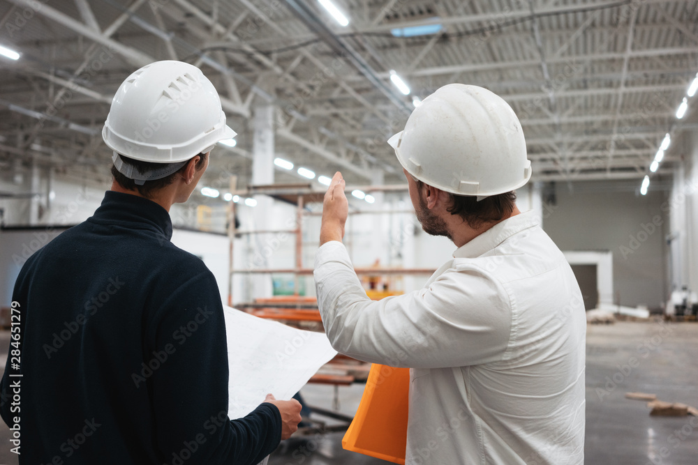 Architect and builder look on blueprint building under construction ...