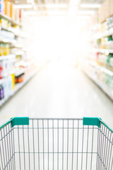 Empty shopping cart or pushcart in supermarket aisle. Buying goods or products in grocery store. Shopping concept