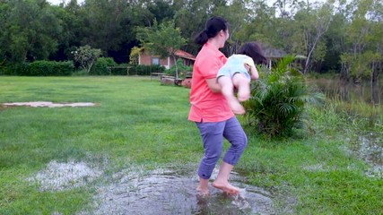 Wall Mural - Slow motion. Mother enjoying with her child. Happy asian girl having fun at lake.