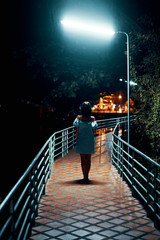 Wall Mural - Young lonely woman walking on the bridge at night