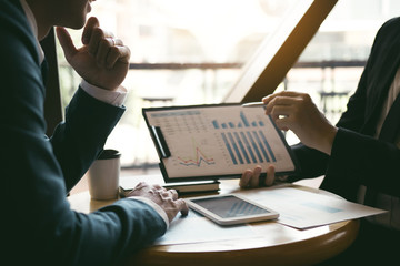 Two business partnership coworkers analysis strategy and gesturing with discussing a financial planning graph and company budget during a budget meeting in office room.