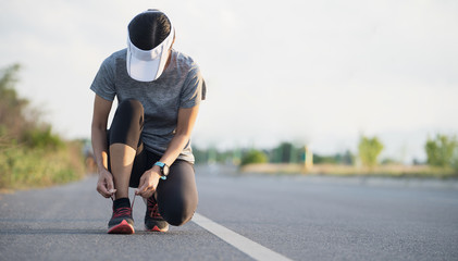 Wall Mural - Running shoes runner woman tying laces for autumn run in forest park. Runner trying running shoes getting ready for run. Jogging girl exercise motivation heatlh and fitness.