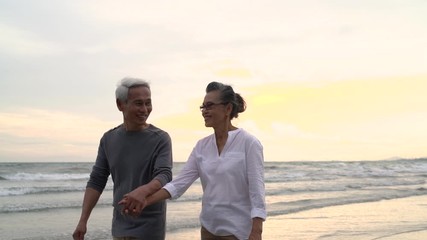 Wall Mural - Asian couple senior elder retire resting relax holding hand walking at sunset beach honeymoon family together happiness people lifestyle, Slow motion footage