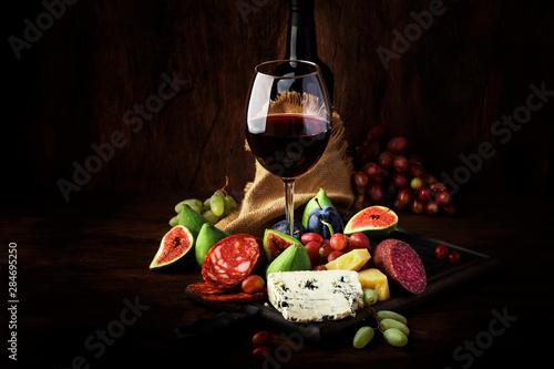 Fotografía Red wine glass and appetizers, cheese, salami, figs, grapes, vintage wooden tabl