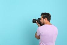 Young Professional Photographer Taking Picture On Light Blue Background. Space For Text