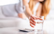 © leszekglasner - Suffering sick woman in bed taking pills and glass of water