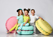 © FAB.1 - Three friends of triplets - two girls and a boy in bright clothes have fun at the birthday party fun room decoration candy macarons