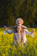 © olga_polyanskaya - The concept of parenting. Beautiful mother and daughter on a yellow rape field