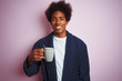 © Krakenimages.com - Afro american man wearing pajama drinking coffee standing over isolated pink background with a happy face standing and smiling with a confident smile showing teeth