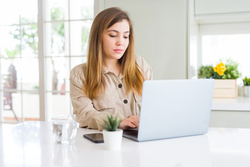 Wall Mural - Beautiful young woman using computer laptop with a confident expression on smart face thinking serious