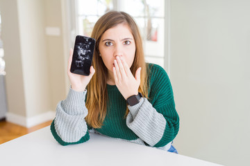 Sticker - Beautiful young woman holding broken smartphone cover mouth with hand shocked with shame for mistake, expression of fear, scared in silence, secret concept