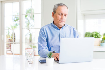 Wall Mural - Handsome senior man using computer laptop working on internet with a confident expression on smart face thinking serious