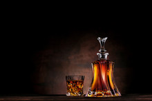 Glass Of Whiskey With Ice And Decanter On Dark Wood Background