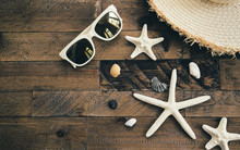 Summer Composition With Sunglasses, Straw Hat, Starfishes And Shells On Wooden Table. Vacation And Travel Concept