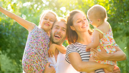 Happy joyful family. Young parents and they little kids having fun outdoors in autumn park