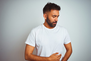 Wall Mural - Young indian man wearing t-shirt standing over isolated white background with hand on stomach because indigestion, painful illness feeling unwell. Ache concept.