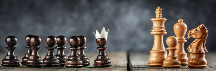 small courageous pawn with fake paper crown costume leading others into battle against the enemy - b