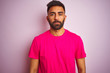 © Krakenimages.com - Young indian man wearing t-shirt standing over isolated pink background Relaxed with serious expression on face. Simple and natural looking at the camera.