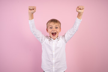 Portrait of cute trendy stylish kid astonished impressed aims contest lottery fortune, scream omg, wow, unbelievable unexpected raise fists shout wear white modern outfit isolated pink background