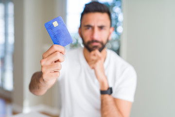 Sticker - Handsome hispanic man holding credit card serious face thinking about question, very confused idea