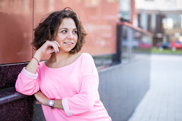 Young Caucasian woman looking at someone leaned an elbow on the wall.