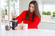© Krakenimages.com - Young beautiful woman making morning coffee smiling, preparing a cup of latte for breakfast