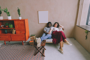 Loving interracial couple relaxing in chair in home interior.