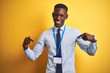 © Krakenimages.com - African american businessman wearing identification card over isolated yellow background looking confident with smile on face, pointing oneself with fingers proud and happy.