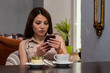© Yakov - Beautiful thoughtful woman using a mobile phone in cafe. Reading news or SMS