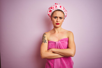 Sticker - Young beautiful woman wearing towel and bath hat after shower over pink isolated background skeptic and nervous, disapproving expression on face with crossed arms. Negative person.