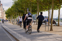 People Ride E-scooters, Trendy Urban Transportation With Eco Friendly Sharing  Mobility Concept, And Bicycle On Bicycle Lane At Promenade Riverside Of Rhine River In Düsseldorf, Germany.