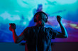 © Anton - Girl gamer playing games in the headphones on a large screen, with bright light and a dark room. .bright background