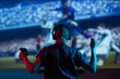 © Anton - Soccer game, girl gamer playing a game in football headphones on a big screen, with bright light and a dark room. Gameplay, streaming, e-sports.