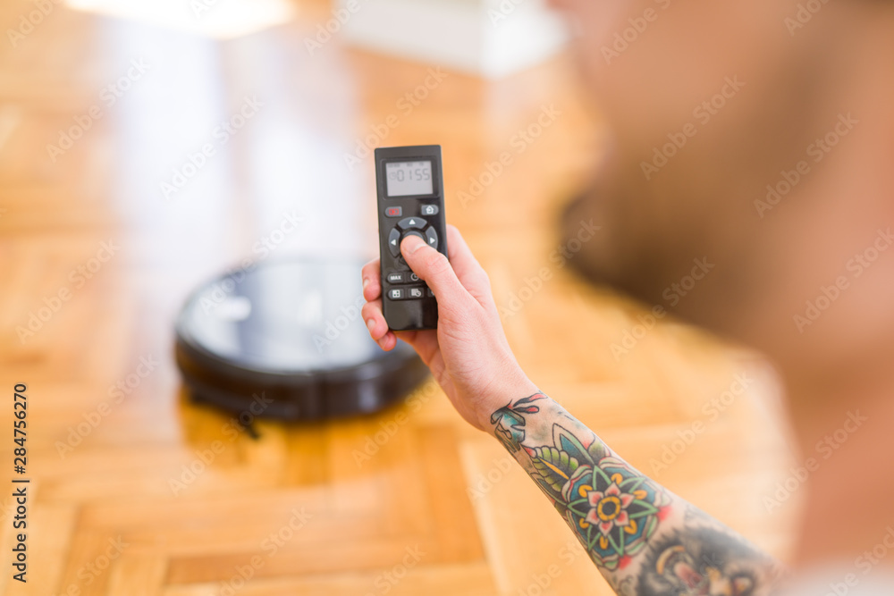 Close up of man hands controling automatic vacuum cleaner using electronic control of the mopping robot