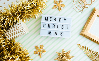 Wall Mural - Merry christmas onl lightbox background.top view of sparkling gold tinsel,ball,ornament decorate on green strip line table.holiday celebration greeting card.