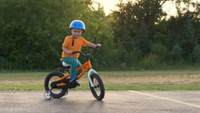 Cute Little Boy ( Two Years Old Child) Is Riding Bike. Kid In Orange T-shirt And Blue Helmet. Orange Kids Bicycle. First Experience, Childhood Memories