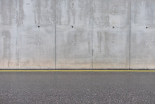Concrete Gray Wall And Asphalt Road With A Yellow Line