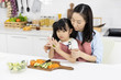 © xreflex - Happy Asian family Mother and child daughter are preparing the salad and cutting vegetables. cooking food in kitchen at home. Healthy food concept