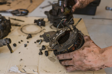 Technician repair old automotive power generator alternator for car in garage.