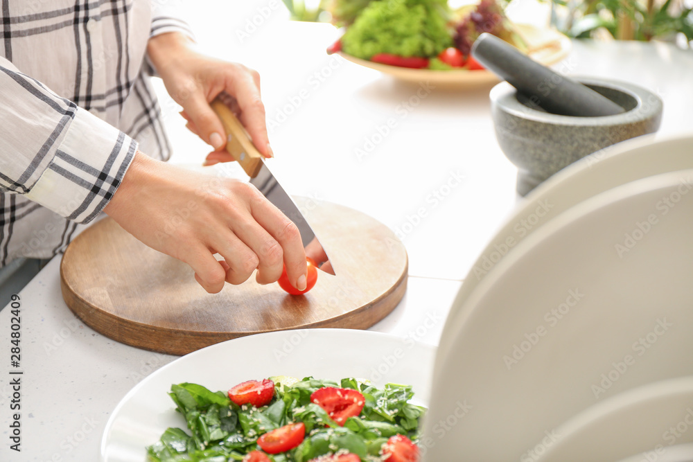 Woman preparing tasty strawberry spinach salad at table