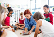 © Halfpoint - A group of small school kids with teacher sitting on the floor in class, learning.