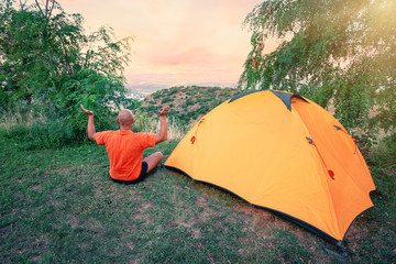Wall Mural - man practices yoga near an orange tent on hill