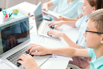 Wall Mural - Clever learners of middle school touching keys of laptop keypad