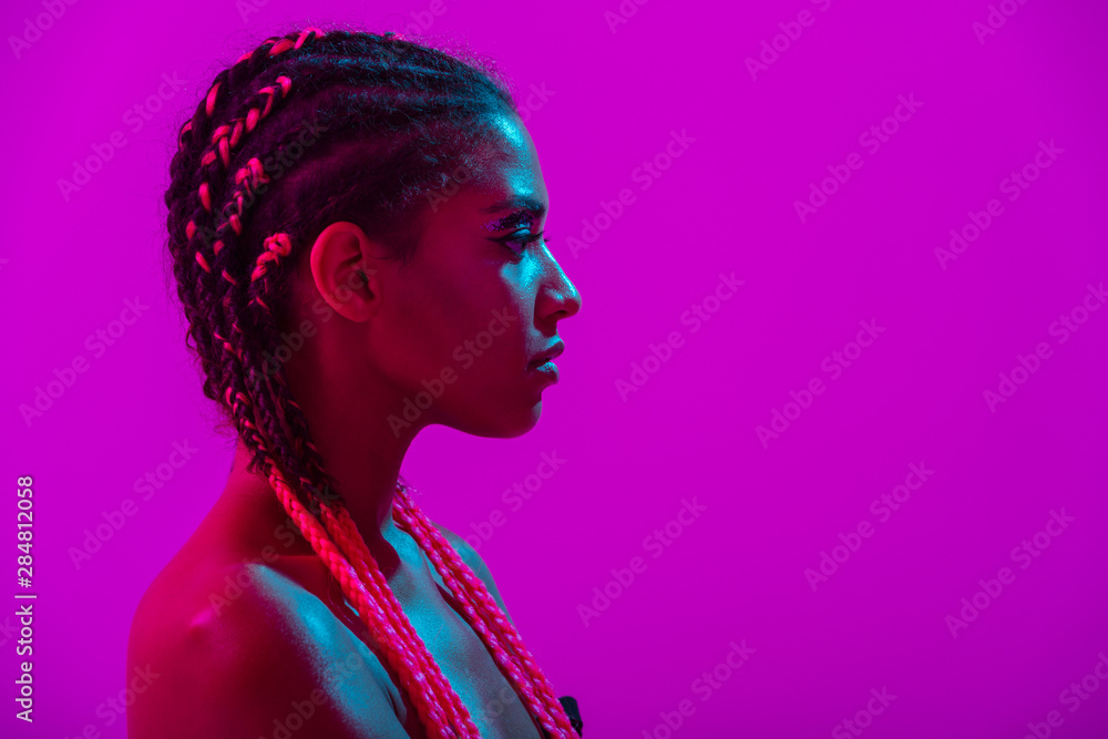 Young african naked woman posing isolated over purple neon lights wall background - obrazy, fototapety, plakaty 